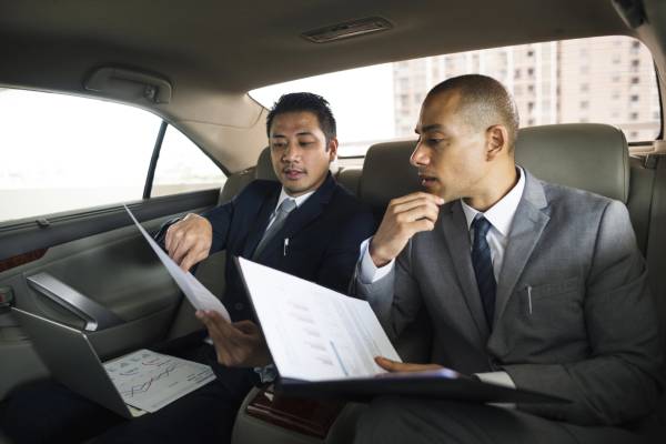 Business professionals reviewing documents in a luxury vehicle rear seat